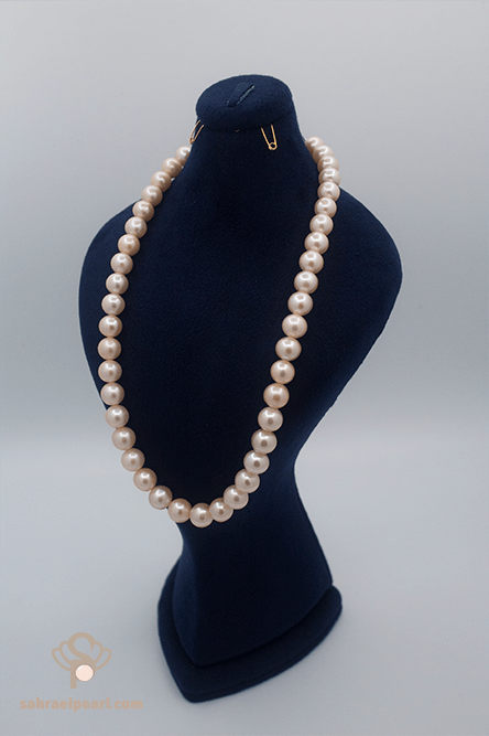 گردنبند مروارید آب شیرین صورتی با دانههای ۹ تا ۹٫۵ میلیمتری (کیفیت AAA) بر روی استند مخملی سرمهای