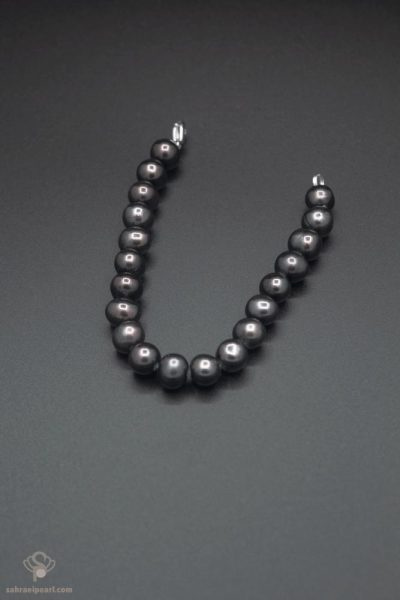 دستبند مروارید آب شیرین سیاه با دانه‌های کروی ۹ تا ۱۰ میلی‌متری (کیفیت AAA) روی پس‌زمینهٔ خاکستری تیره