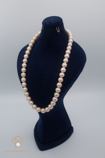 گردنبند مروارید آب شیرین صورتی با دانه‌های ۹ تا ۹٫۵ میلی‌متری (کیفیت AAA) بر روی استند مخملی سرمه‌ای